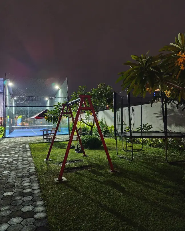 Swing set on the lawn by the courts